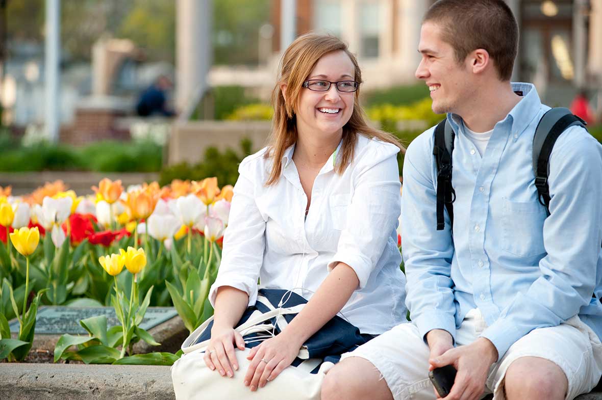 Two students sitting by tulips.